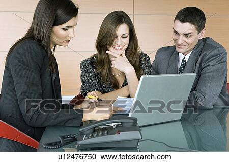 Professional woman looking over paper with couple View Large Photo Image Stock Image - Professional woman looking over paper with couple. Fotosearch