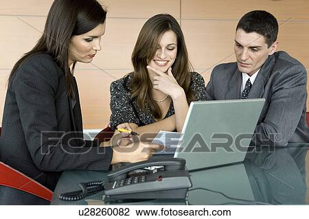 Stock Image - Professional woman looking over paper with couple. Fotosearch