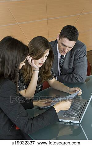 Stock Photo - Professional woman looking over paper with couple. Fotosearch