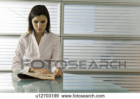 Professional woman reading newspaper at desk View Large Photo Image Stock Photo - Professional woman reading newspaper at desk. Fotosearch