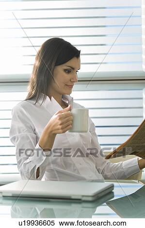 Professional woman reading newspaper and drinking coffee View Large Photo Image Stock Photography - Professional woman reading newspaper and drinking coffee. Fotosearch