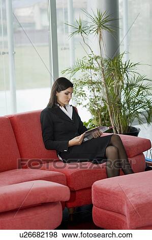 Stock Photo - Professional woman sitting on couch reading. Fotosearch