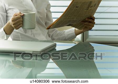 Stock Photograph - Professional woman with newspaper and coffee cup. Fotosearch