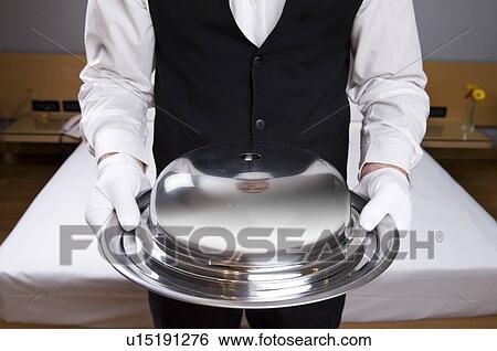 Stock Photograph - Torso of waiter holding covered silver platter. Fotosearch