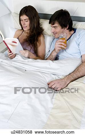 Stock Photo - Young couple in bed relaxing. Fotosearch