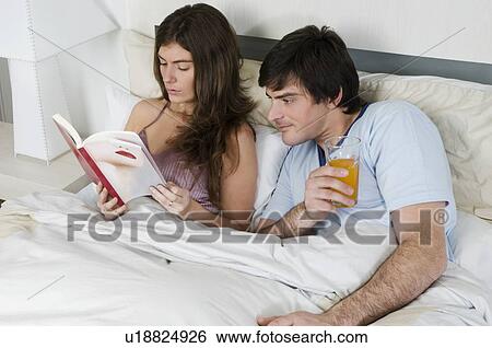 Young couple in bed relaxing View Large Photo Image Stock Photograph - Young couple in bed relaxing. Fotosearch