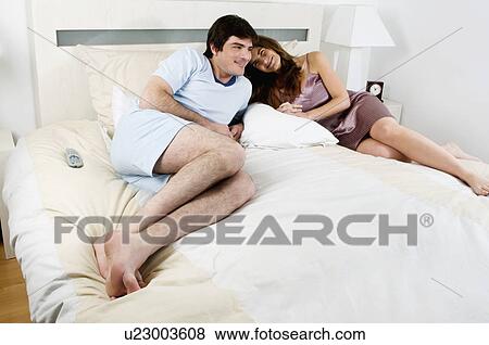 Young couple lying in bed View Large Photo Image Stock Photo - Young couple lying in bed. Fotosearch