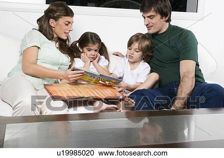 Young couple on couch with children reading View Large Photo Image Stock Image - Young couple on couch with children reading. Fotosearch