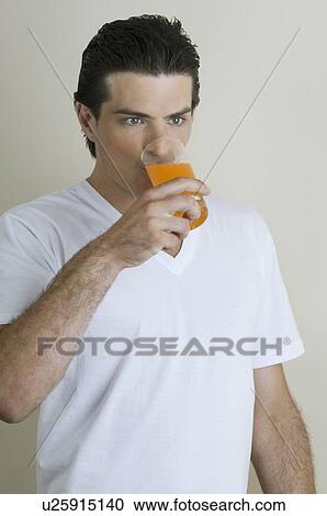 Young man drinking a glass of juice View Large Photo Image Stock Image - Young man drinking a glass of juice. Fotosearch