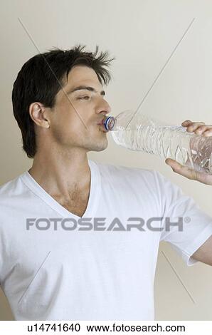 Young man drinking bottled water View Large Photo Image Stock Image - Young man drinking bottled water. Fotosearch