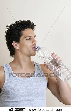 Young man drinking bottled water View Large Photo Image Stock Image - Young man drinking bottled water. Fotosearch