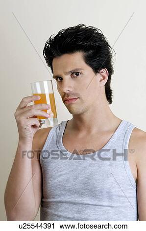 Stock Image - Young man holding a glass of juice. Fotosearch