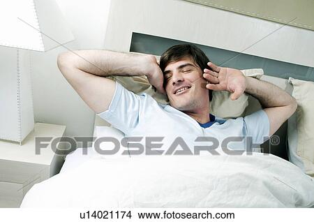 Young man in bed stretching View Large Photo Image Picture - Young man in bed stretching. Fotosearch