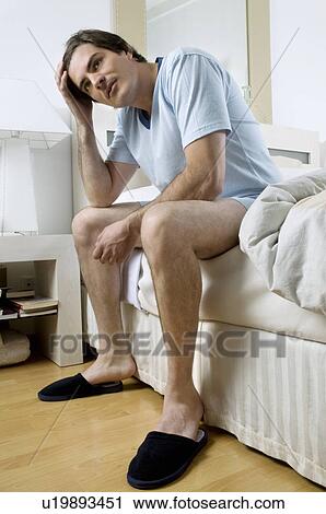 Young man in slippers sitting on bed View Large Photo Image Stock Image - Young man in slippers sitting on bed. Fotosearch
