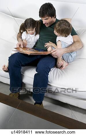 Young man on couch with children reading View Large Photo Image Stock Image - Young man on couch with children reading. Fotosearch