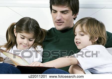 Young man on couch with children reading View Large Photo Image Stock Image - Young man on couch with children reading. Fotosearch
