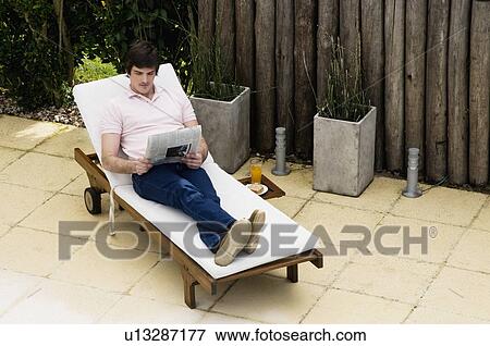 Stock Photo - Young man reading by the swimming pool. Fotosearch