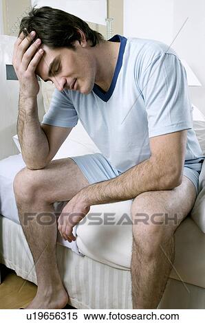 "Young man sitting on bed, head on hand" View Large Photo Image Stock Photography - "Young man sitting on bed, head on hand". Fotosearch