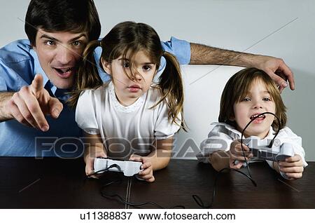 Young man with children playing video game View Large Photo Image Stock Photo - Young man with children playing video game. Fotosearch