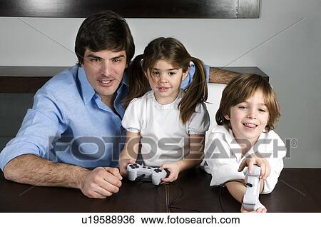 Young man with children playing video game View Large Photo Image Stock Photograph - Young man with children playing video game. Fotosearch