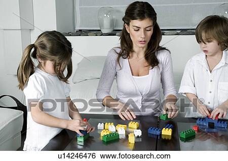 Young woman and boy and girl playing with building blocks View Large Photo Image Stock Photograph - Young woman and boy and girl playing with building blocks. Fotosearch