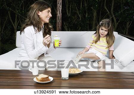 Young woman and girl having breakfast outdoors View Large Photo Image Stock Image - Young woman and girl having breakfast outdoors. Fotosearch