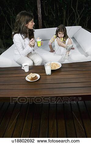 Young woman and girl having breakfast outdoors View Large Photo Image Stock Image - Young woman and girl having breakfast outdoors. Fotosearch