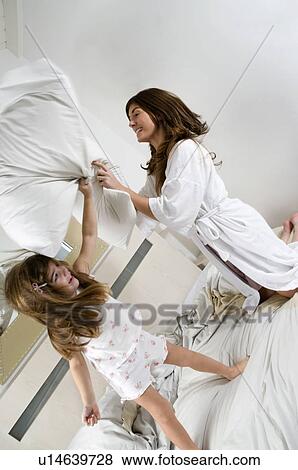 Stock Photo - Young woman and girl on bed playing. Fotosearch