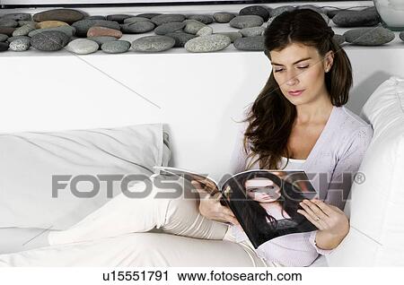 Young woman on couch reading magazine View Large Photo Image Stock Image - Young woman on couch reading magazine. Fotosearch