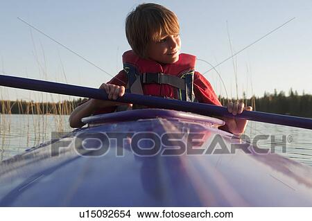 Picture - 10 year old boy in kayak looks toward sunset, Lake Katherine, Riding Mountain National Park, Manitoba. Fotosearch