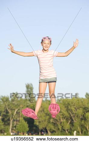 Stock Image - 11 year old girl with swim fins jumping high, Winnipeg, Canada. Fotosearch