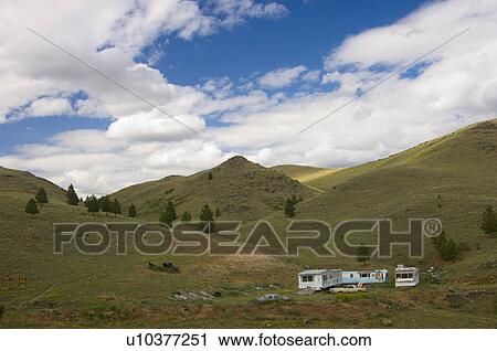 Stock Image - Abandoned mobile homes with junk in beautiful green hills, Montana, USA. Fotosearch