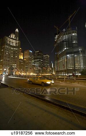 Stock Photograph - Blurred taxi driving with cityscape background at night, Chicago, USA. Fotosearch