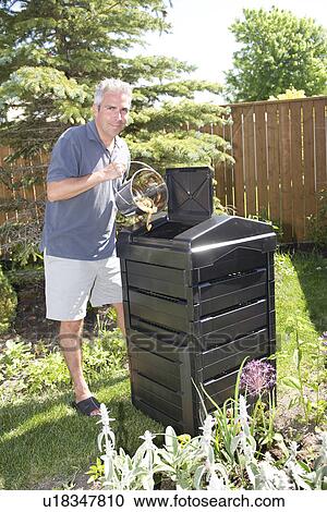Stock Image -  Boy with recycling bin at back door of home, Winnipeg, Canada. Fotosearch