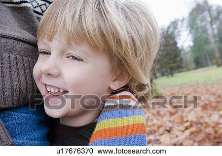 Stock Image - Close-up young boys face as he embraces mom's waist, Vancouver, British Columbia. Fotosearch