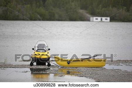 Stock Photo - Contradiction of seaons; in this scene, a snowmobile sits along the summer shores of the Great Slave Lake. Photographed in Yellowknife, Northwest Territories.. Fotosearch