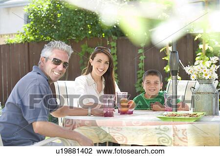 Stock Image - Couple and son seated at outdoor table, Winnipeg, Canada. Fotosearch