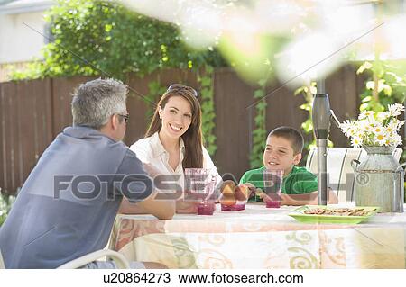 Stock Image - Couple and son seated at outdoor table, Winnipeg, Canada. Fotosearch