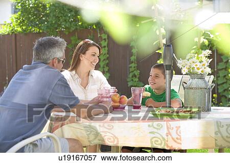 Stock Photo - Couple speak with son at outdoor table, Winnipeg, Canada. Fotosearch