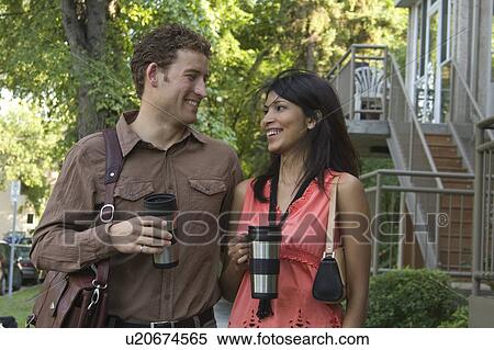Stock Photography - Couple with re-usable coffee containers walking down residential street, Winnipeg, Canada. Fotosearch