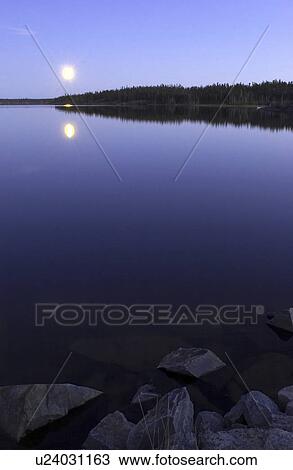 Stock Image - Early October moonrise over Pontoon Lake, which is located down the Ingraham Trail in Northwest Territories, Canada.. Fotosearch