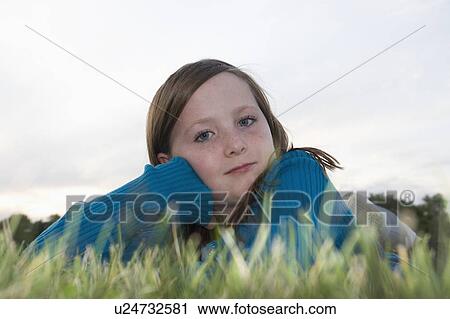 Stock Image - Eight year old girl at twilight lying in grass, Winnipeg, Canada. Fotosearch
