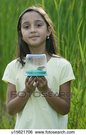 Stock Photograph - Eight year old girl holding frog in collecting jar in wetland, Winnipeg, Canada. Fotosearch