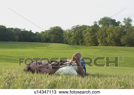 Stock Image - Eight year old girl laying down on grass in park, Winnipeg, Canada. Fotosearch
