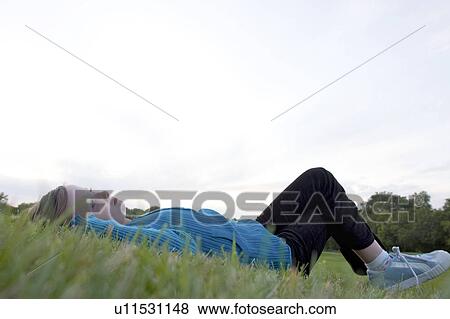 Stock Photo - Eight year old girl lying on back in grass looking upward, Winnipeg, Canada. Fotosearch