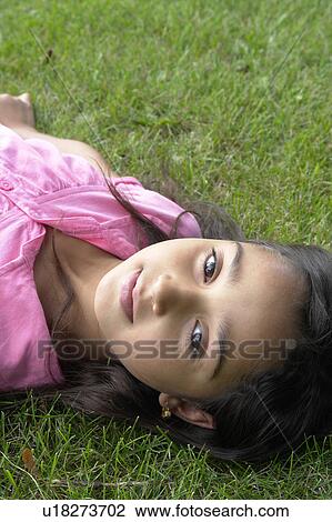 Stock Image - Eight year old girl lying on greass, Winnipeg, Canada. Fotosearch