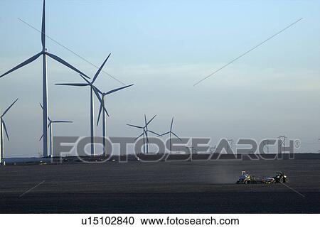 Farming equipment dwarfed by array of wind turbines View Large Photo Image Stock Image - Farming equipment dwarfed by array of wind turbines. Fotosearch