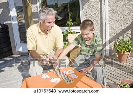 Stock Photo - Father and son playing cribbage on deck, Winnipeg, Canada. Fotosearch