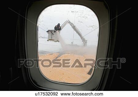 Stock Image - Flying out of a snow-bogged Edmonton, Alberta (a record 25 centimetres of March snow fell on the day before), a flight faces an hour delay while a crew de-ices the aircraft.. Fotosearch