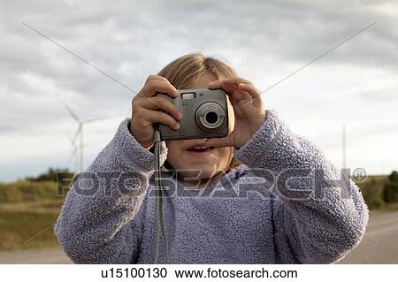 Stock Image - Girl checking back of digital camera in front of wind turbines, Tiverton, Bruce Peninsula, Ontario. Fotosearch